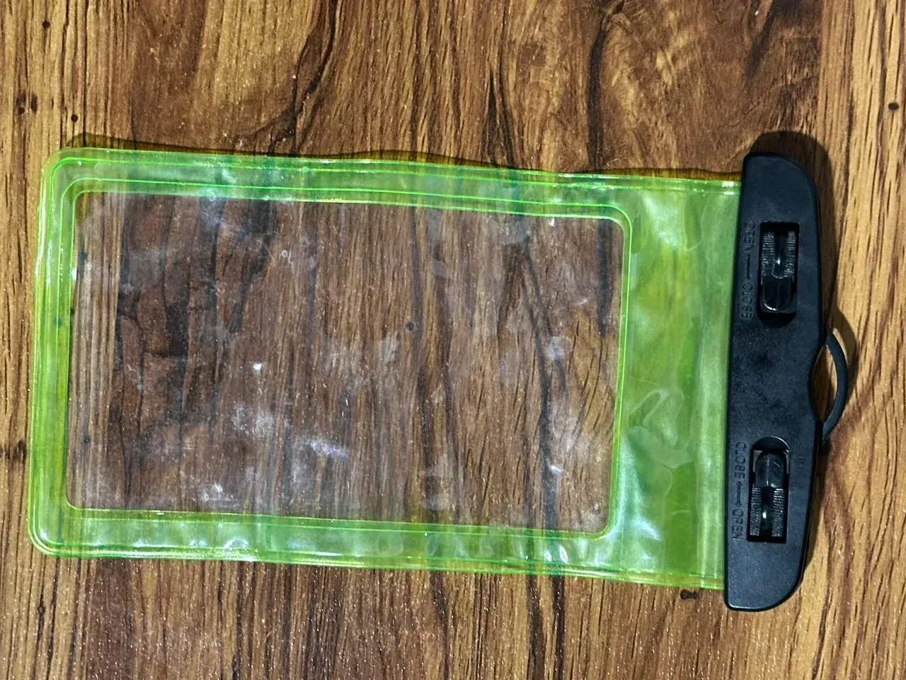 Alt text: Green waterproof phone pouch with a clear touchscreen window and secure locking clips.