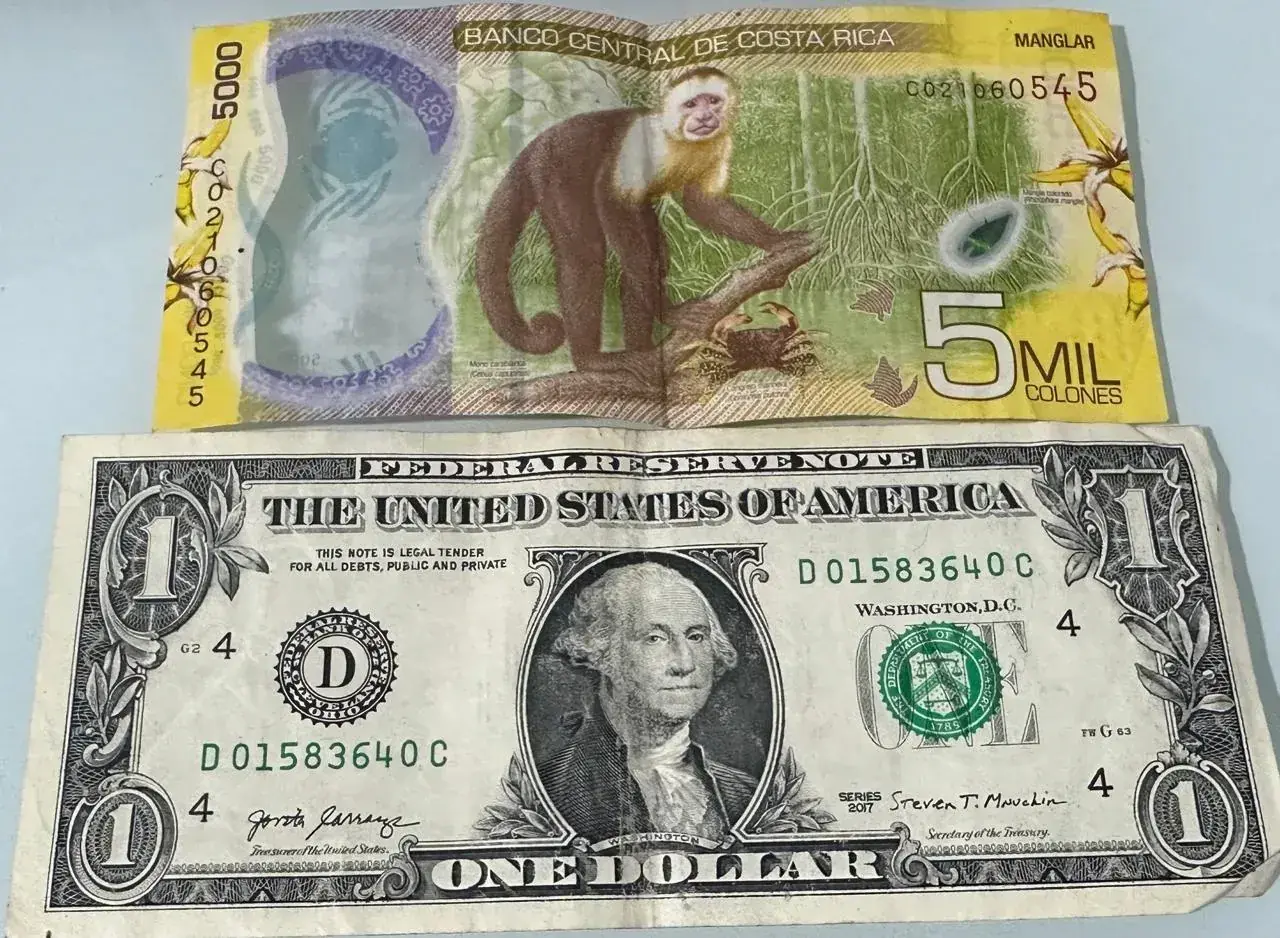 Costa Rican 5,000-colón banknote beside a US one-dollar bill