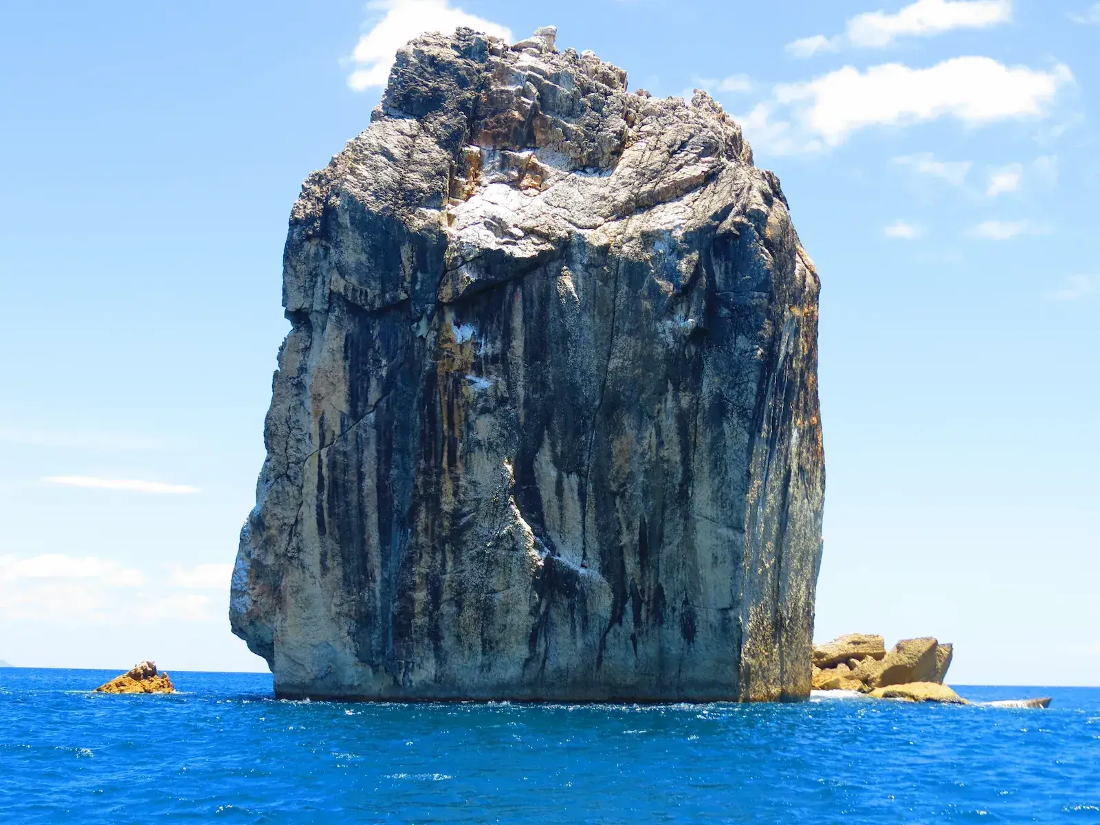 Large rocky sea stack rising from the blue Pacific Ocean along the Costa Rican coast.
