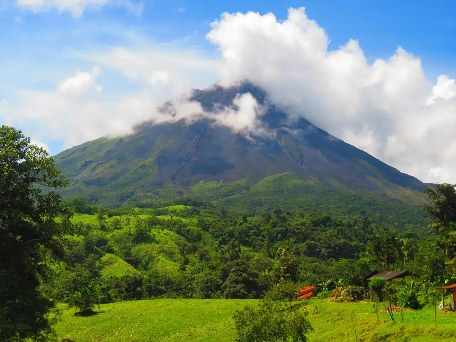 Arenal Volcano rising above lush green rainforest and farmland near La Fortuna, Costa Rica.
