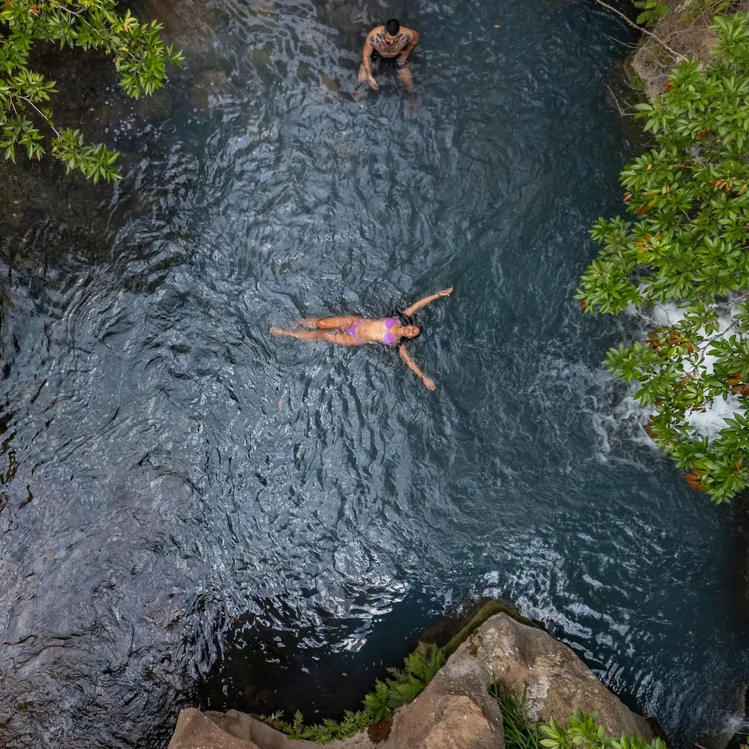 Traveler swimming in a natural pool surrounded by tropical forest in Costa Rica